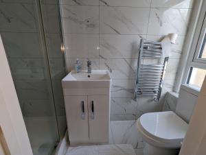 uma casa de banho com um lavatório, um chuveiro e um WC. em Mile End- Prime location em Londres