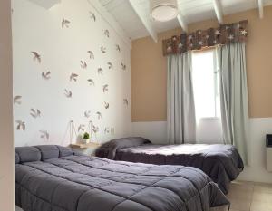 2 camas en una habitación con pájaros en la pared en Tehuelches del sur en Puerto Madryn