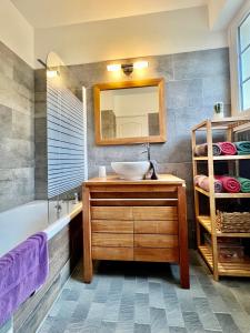 een badkamer met een wastafel, een bad en een spiegel bij La Rose Des Vents in Grandcamp-Maisy