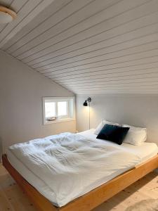 a bedroom with a large white bed with a ceiling at Lovely, bright apartment overlooking nature in Fiskebäckskil