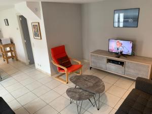 a living room with a tv and a red chair at Huisjes aan zee in De Haan