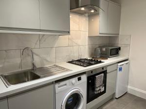 a kitchen with a stove top oven next to a sink at Luxury 1 bed apartment + 1 Sofa Bed Can sleep Up To 4 People 5 Mins Barnet Station Free Parking in Barnet