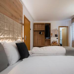 una camera da letto con un grande letto bianco con cuscini bianchi di Hotel Irma a Folgaria