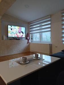 a living room with a tv and two cups on a table at Tina in Užice