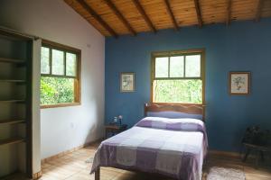 1 dormitorio azul con 1 cama y 2 ventanas en Ytororô O som das águas, en Paraty