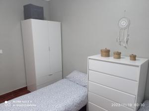 a white bedroom with a bed and a dresser at La viña in Melilla