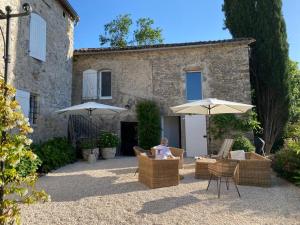a woman sitting in a chair under two umbrellas at Magnifique Mas Cevenol in Anduze