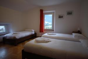 ボルミオにあるCasa Bellottiのベッド3台と窓が備わる客室です。