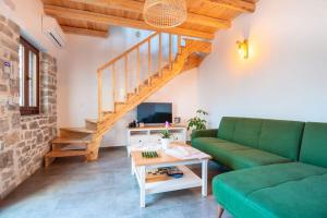 Odysseus House في Límnai: غرفة معيشة مع أريكة خضراء ودرج