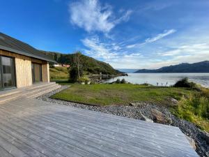 a house with a wooden walkway next to a body of water at Superior Cabin with Private Beach Lofoten 