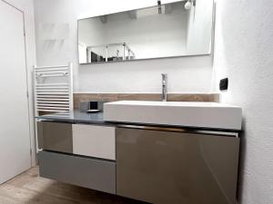 La salle de bains est pourvue d'un lavabo blanc et d'un miroir. dans l'établissement Grazioso appartamento Aosta, à Aoste