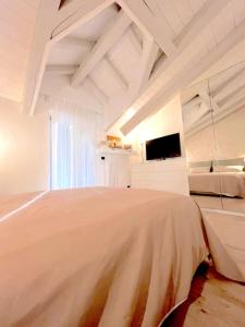 a white bedroom with a large bed and a tv at Grazioso appartamento Aosta in Aosta