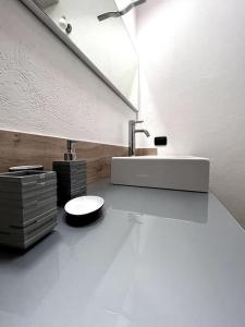 La salle de bains blanche est pourvue d'un lavabo et d'un miroir. dans l'établissement Grazioso appartamento Aosta, à Aoste