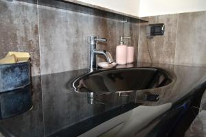 La salle de bains est pourvue d'un lavabo noir. dans l'établissement Grazioso appartamento Aosta, à Aoste