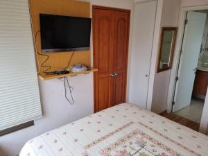 1 dormitorio con 1 cama y TV en la pared en Delpino Propiedades Sector Casino, en Viña del Mar