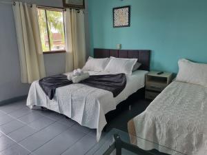 a bedroom with two beds and a teddy bear on the bed at Hotel Pousada Vento Leste in Cananéia