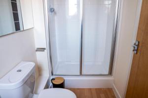 uma casa de banho branca com um chuveiro e um WC. em Lovely 2 bedrooms apartment em Portsmouth