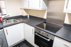 cocina con armarios blancos y fogones negros en Lovely 2 bedrooms apartment en Portsmouth