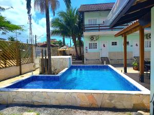 a swimming pool in front of a house at Recanto Maranduba in Ubatuba