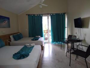 a room with two beds and a table and a television at Paradise Island Beach Resort in Punta Rucia