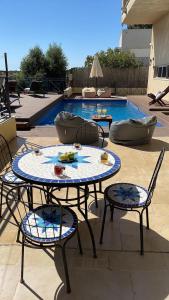 een tafel en stoelen met eten erop naast een zwembad bij La Villa Toscana: Pool & Elah Valley vineyard view in Adderet