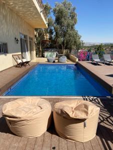 una piscina con 2 pufs frente a una casa en La Villa Toscana: Pool & Elah Valley vineyard view en Adderet