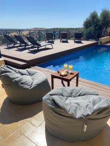 a pool with two bean chairs and a table next to a pool at La Villa Toscana: Pool & Elah Valley vineyard view in Adderet