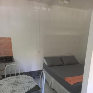 Dormitorio pequeño con cama y mesa en Flat em Búzios com ar, en Búzios