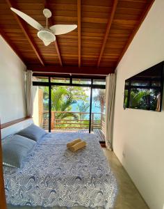 een slaapkamer met een bed en een plafondventilator bij Casas Do Mar in Ilhabela