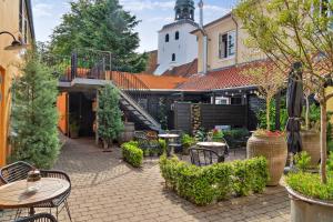 un patio con mesas y sillas y un edificio en Hotel På Torvet en Ærøskøbing