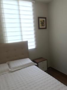 um quarto com uma cama branca e uma janela em Departamento de estreno en 1er piso en Condominio em Piura