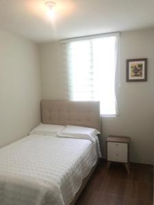 1 dormitorio con cama blanca y ventana en Departamento de estreno en 1er piso en Condominio, en Piura