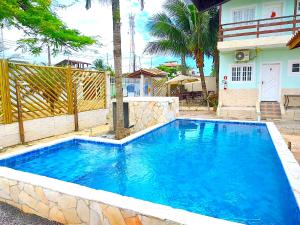 a large blue swimming pool in front of a house at Recanto Maranduba in Ubatuba