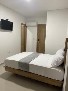 1 dormitorio con 1 cama y TV en la pared en Hotel El Faro, en Cartagena de Indias