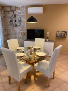 a dining room with a glass table and white chairs at Apartman Olive in Tar