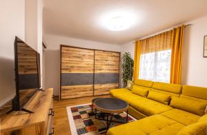 a living room with a yellow couch and a tv at DieLangthalers Exklusive Oase in Seiersberg