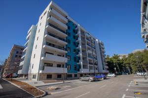 a tall apartment building with cars parked in a parking lot at Apartman Kuburica in Trebinje
