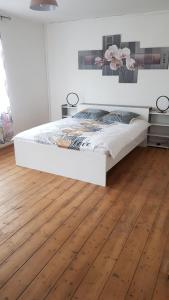 a bedroom with a white bed and a wooden floor at La Maison de Lucette in Fourmies