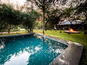 een zwembad in een tuin met een vuurplaats bij Ukuthula @ the Kruger in Marloth Park