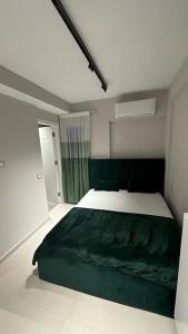 um quarto com uma cama grande e um cobertor verde em Host Apartament Elio em Tirana