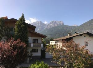 a building with mountains in the background with trees at The Dolomiti View in Debant