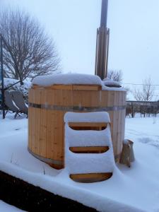 a wooden barrel covered in snow in a yard at La maison horlogère , spas et bain nordique in Les Fontenelles