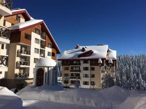 a building covered in snow next to a building at Apartment Dream Pamporovo in Pamporovo