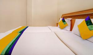 a bedroom with a white bed with colorful pillows at Itsy By Treebo - Coastal Grand Sathyam in Fort