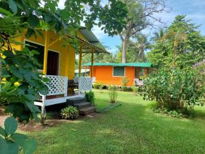 uma casa amarela e laranja com um banco no quintal em All Rankins Eco-Lodge em Tortuguero