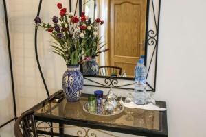 una mesa de cristal con un jarrón de flores y un espejo en HOTEL LA POMME ZAIDA en Zeïda