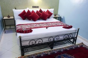 1 dormitorio con 1 cama grande con almohadas rojas en HOTEL LA POMME ZAIDA, en Zeïda