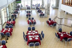 une salle remplie de tables et de chaises avec des assiettes rouges et blanches. dans l'établissement HOTEL LA POMME ZAIDA, à Zeïda