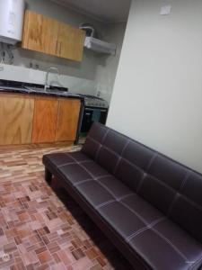 プエルトモントにあるApartamento por diaのキッチン横のリビングルームに茶色のソファ