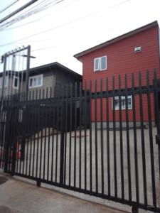 a black fence in front of a red building at Apartamento por dia in Puerto Montt